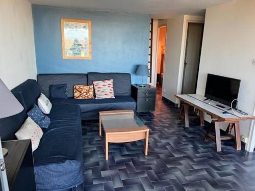 un salon avec un canapé bleu et une table dans l'établissement Appartement T3 à Cap d'Agde, 6 pers, au bord de la plage avec parking et terrasse - FR-1-749-13, au Cap d'Agde