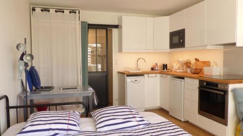 une petite cuisine avec des armoires blanches et un lit dans l'établissement Studio les pieds dans l’eau à Penthièvre, à Saint-Pierre-Quiberon