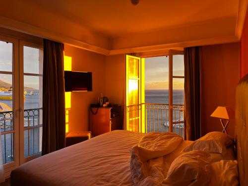 a bedroom with a bed and a view of the ocean at Hôtel Des Gouverneurs in Bastia
