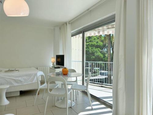 Cette chambre blanche dispose d'une table, de chaises et d'un balcon. dans l'établissement Studio climatisé 2★, 2 balcons, proche plage, Le Lavandou - FR-1-251-475, au Lavandou