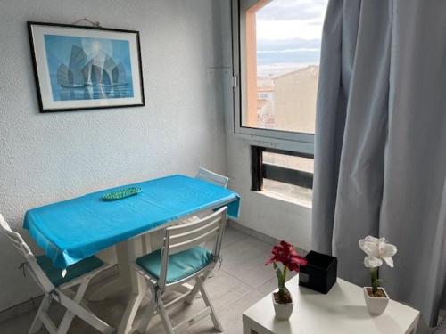 une table bleue et des chaises dans une chambre avec fenêtre dans l'établissement Studio avec Parking et Proche Plage, Animaux Acceptés - FR-1-749-26, au Cap d'Agde