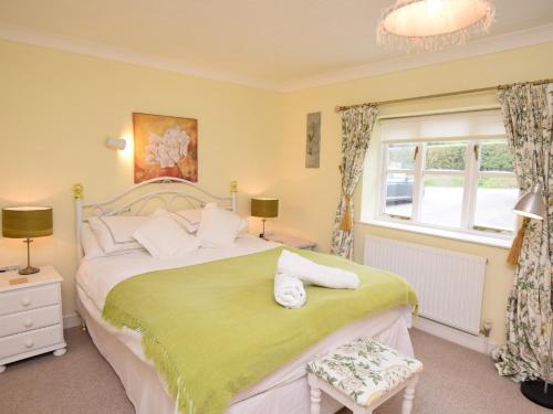 a bedroom with a large bed with a green blanket at 2 Bed in Sherborne 53673 in Chetnole