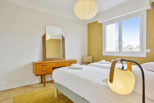 Habitación de hotel con 2 camas y espejo en T3 design et familial avec parking Biarritz proche commodités, en Biarritz