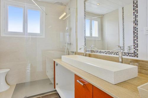 uma casa de banho branca com um lavatório e um chuveiro em T3 design et familial avec parking Biarritz proche commodités em Biarritz