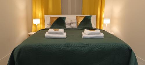 1 cama verde grande con 2 toallas blancas. en Central Cracow Apartments, en Cracovia