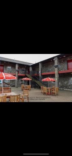 a group of tables with umbrellas in front of a building at DARE VALLEY ACCOMMODATION in Aberdare