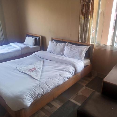 1 dormitorio con 2 camas con sábanas blancas y ventana en Hotel Pacific Pokhara, en Pokhara