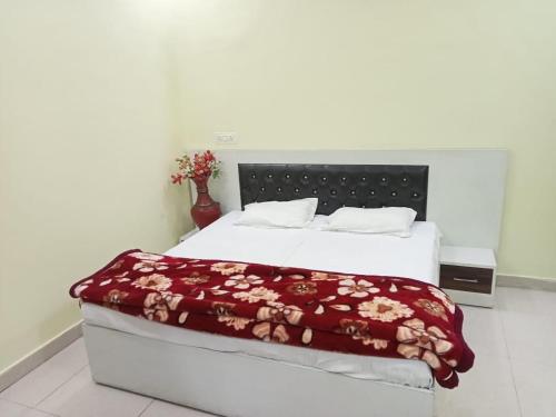 a bedroom with a bed with a red blanket on it at Anand Family Restaurant in Bulandshahr