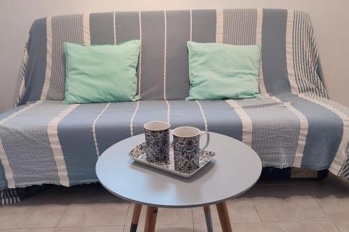 - une table basse avec 2 tasses sur un canapé dans l'établissement Petite Maison des Demoiselles, à Saint-Hilaire-de-Riez