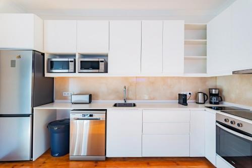 uma cozinha com armários brancos e um frigorífico de aço inoxidável em Guest Inn 1 Boutique House em Lisboa