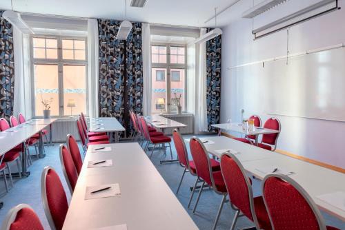 a dining room with white tables and red chairs at First Hotel Statt Örnsköldsvik in Örnsköldsvik