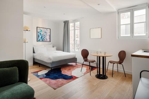 une chambre avec un lit, une table et des chaises dans l'établissement Residence Clichy - Dagobert, à Clichy