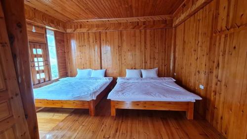 a room with two beds in a wooden cabin at Farmstay alenh Lùng Phình in Lao Cai