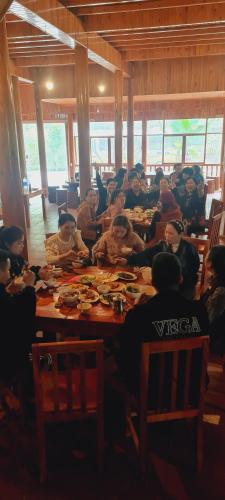 Un groupe de personnes assises à une longue table dans l'établissement Farmstay alenh Lùng Phình, à Lào Cai