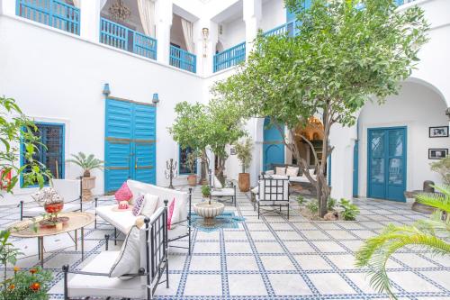 un patio con puertas azules, sillas y árboles en Riad Khalifa, en Marrakech
