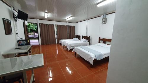 a room with three beds and a desk and a table at Sleep&Go! Cabina Cuadruple en Siquirres Centro -and rafting tour! in Siquirres