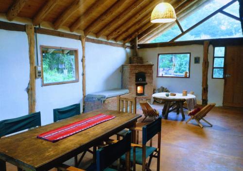 a dining room with a table and a fireplace at Adobe Ecohostel in Villa Meliquina