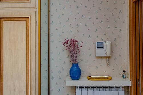 um vaso azul com flores na parede em Porta Romana Suite di Charme em Milão