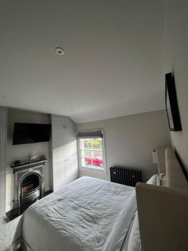 um quarto branco com uma cama e uma lareira em Regatta-Ready Escape em Henley on Thames