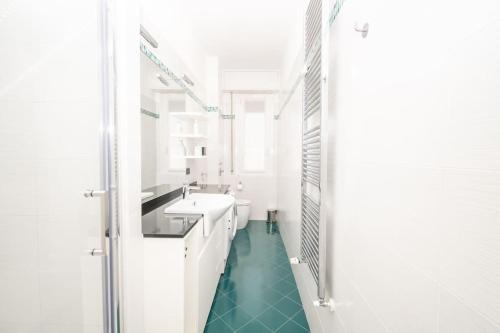 La salle de bains blanche est pourvue d'un lavabo et d'un miroir. dans l'établissement Grazioso appartamento in Bicocca con AC e Wi-fi, à Milan