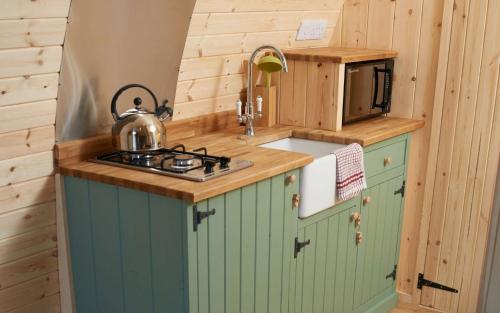 a small kitchen with a stove and a microwave at Mountain Edge Resort Mega pod 1 with Hot Tub in Church Stretton