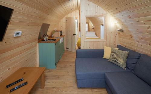 a living room with a blue couch in a cabin at Mountain Edge Resort Mega pod 1 with Hot Tub in Church Stretton