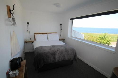 a bedroom with a bed and a large window at Ocean View Bar & Rooms in Laide