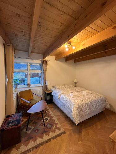 1 dormitorio con 1 cama, 1 silla y 1 ventana en Curry house rooms, en Seyðisfjörður