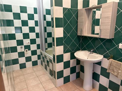Olbia via modena في أولبيا: حمام أخضر وبيضاء مع حوض ومرآة