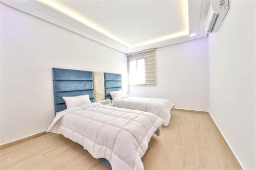 twee bedden in een kamer met witte muren bij Cosy Apartment 2 Bedrooms Golf City in Marrakesh