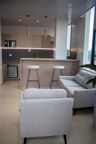 a living room with a white couch and a kitchen at Hotel Amazonas Suite, Suite Presidencial in Nueva Loja