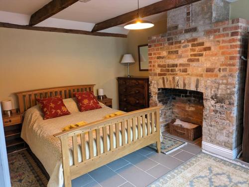 a bedroom with a bed and a brick fireplace at The Fish Loft in Tewkesbury