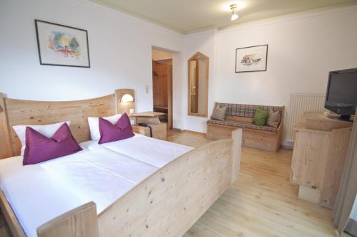 ein Schlafzimmer mit einem großen Bett mit lila Kissen in der Unterkunft Gasthof Sonne in Matrei in Osttirol