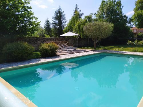 une grande piscine bleue avec une chaise et un parasol dans l'établissement Grande maison familiale 10-12 pers avec piscine privée, à Champagné-les-Marais
