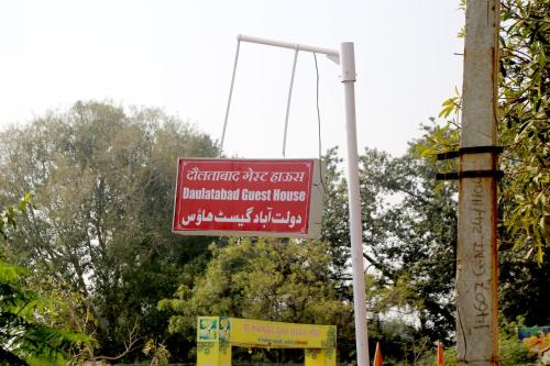 a sign hanging from a pole next to a street at Daulatabad Guest House in Daulatābād