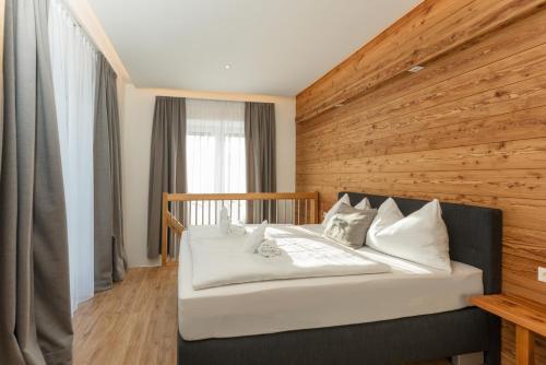ein Schlafzimmer mit einem Bett mit einer Holzwand in der Unterkunft Free Feel Appartements by Schladming-Appartements in Schladming