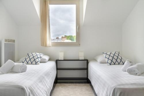 2 camas en una habitación con ventana en Epicea- Spacieux 3 chambres avec parking., en Nantes