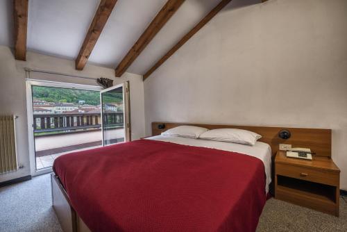 Un dormitorio con una cama grande y una ventana en Hotel Drago, en Mezzocorona