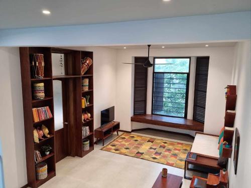 a living room with a window and bookshelves at Still Waters - A Cottage by the Lake! in Boralesgamuwa