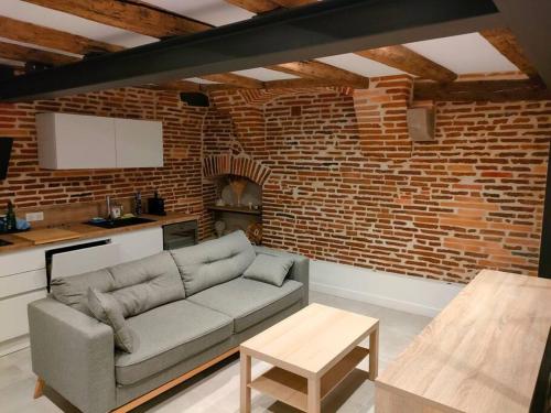 ein Wohnzimmer mit Sofa und Ziegelwand in der Unterkunft Appartement Capitole hypercentre in Toulouse