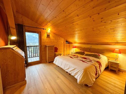 une chambre avec un lit dans une cabane en bois dans l'établissement Duplex spacieux avec terrasse, piscine couverte et cheminée à Samoëns - FR-1-624-9, à Samoëns