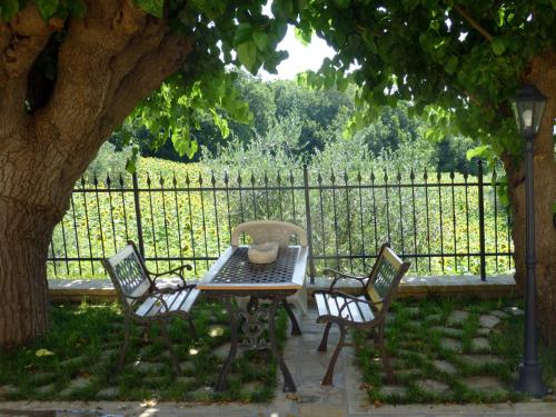 a table and chairs under a tree next to a fence at Country House Le Grazie in Serra San Quirico