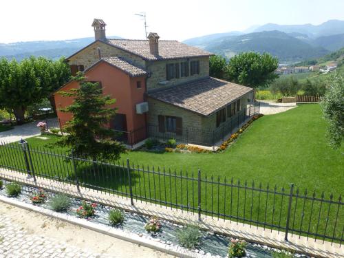 a house with a fence in front of a yard at Country House Le Grazie in Serra San Quirico