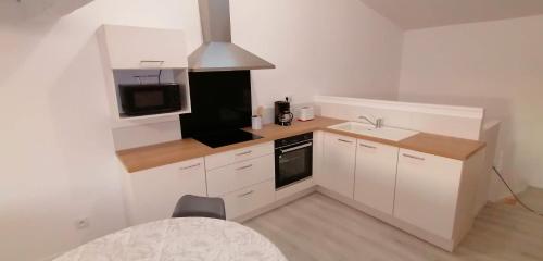 eine kleine Küche mit weißen Schränken und einem Waschbecken in der Unterkunft Appartement 2 chambres in Champdeniers