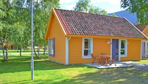 a small yellow cottage with a table and chairs at Lærdal Ferie- og Fritidspark in Lærdalsøyri