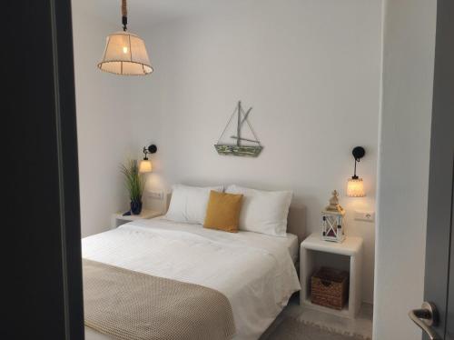 a bedroom with a bed with white sheets and yellow pillows at Krotiri View Paros in Krotiri