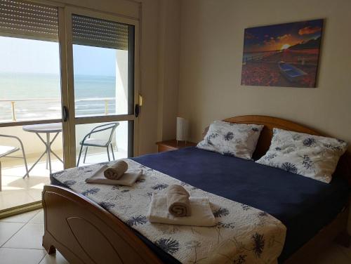 a bedroom with a bed and a balcony with the ocean at Renata Seaview Apartment 310 in Durrës