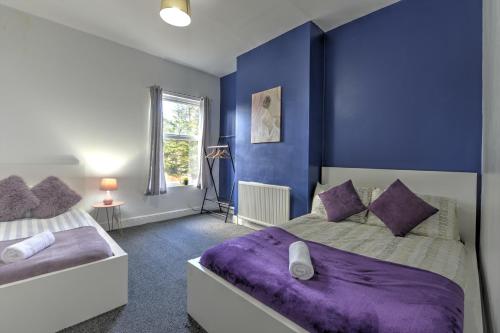 Cosy 3BR Gem, Sleeps 6, Near Town Centre في كوفينتري: غرفة نوم بسريرين وجدار ازرق