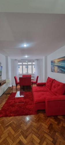 sala de estar con sofá rojo y mesa en Apartamento lateral mar en Río de Janeiro