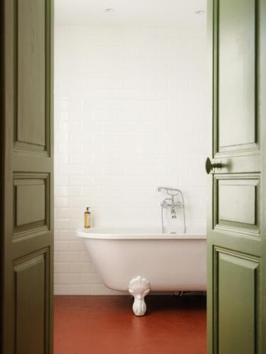 a white bath tub in a bathroom with a door at Demeure Castel Brando Hôtel & Spa in Erbalunga